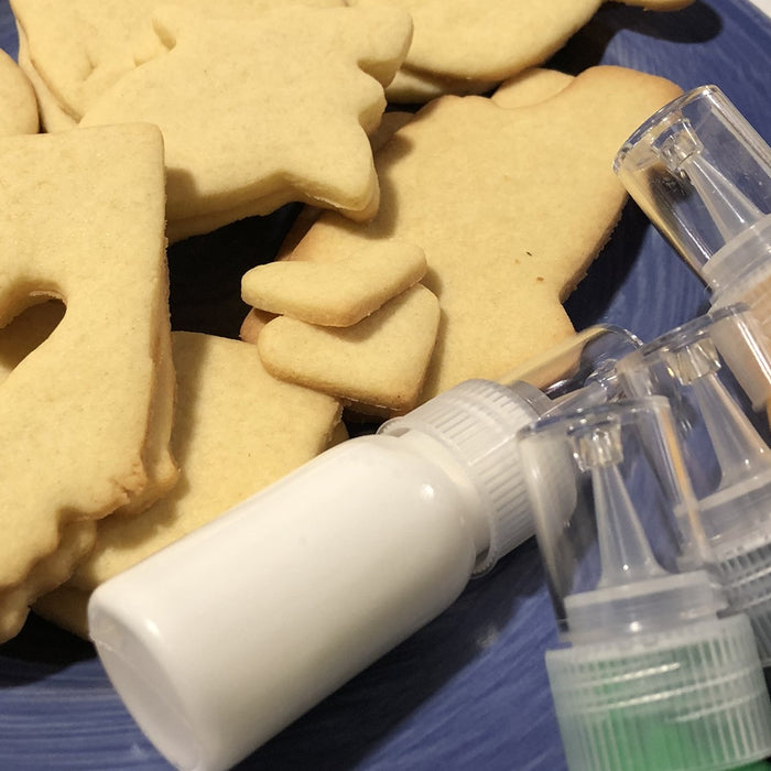 Freshly baked sugar cookies in various shapes, displayed on a blue plate with colorful icing bottles ready for decorating.