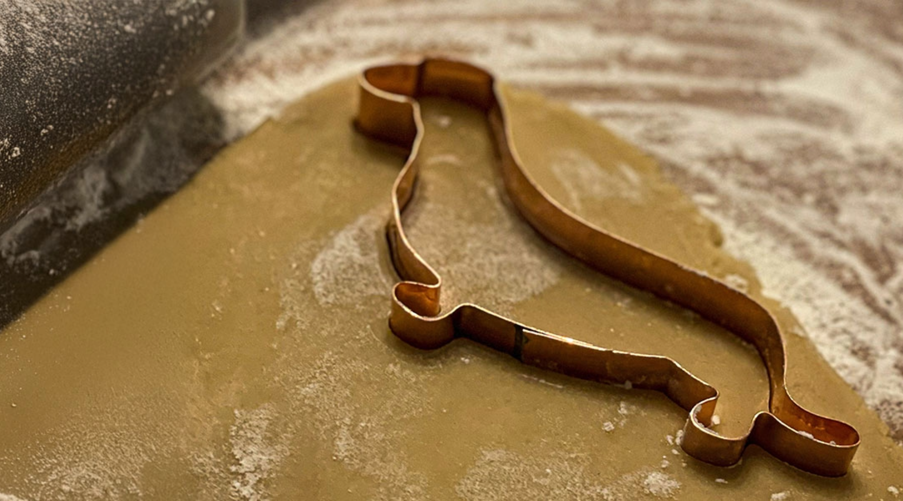 Handmade copper dachshund cookie cutter in action on rolled-out dough, showcasing The Fussy Pup’s unique dog-themed baking tools for cookies and gifts.