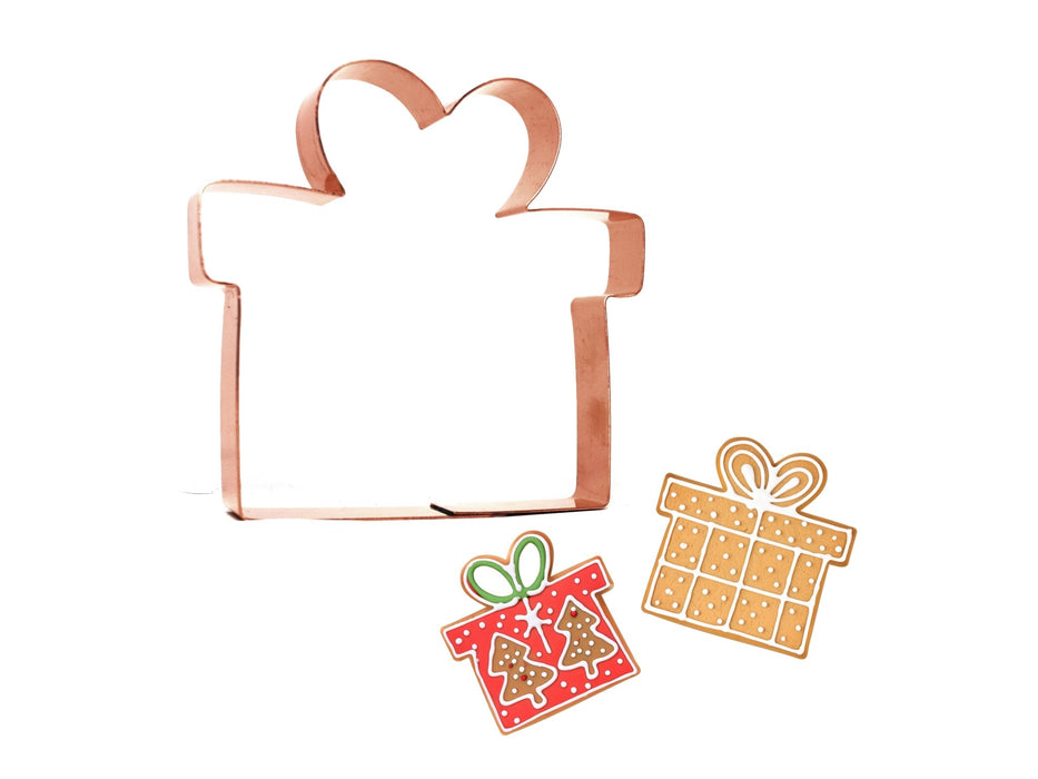 Copper gift box cookie cutter with two decorative gift cookies on a white background