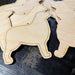 Close-up of laser-cut Bernese Mountain Dog wood shapes made from birch plywood, perfect for painting and crafting holiday ornaments or decorations.