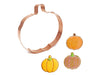 Copper pumpkin-shaped cookie cutter with cut-out pumpkin cookies decorated on a white background
